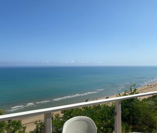 Vista mare con cielo sereno e spiaggia sabbiosa.