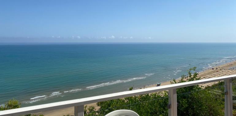 Vista mare con cielo sereno e spiaggia sabbiosa.